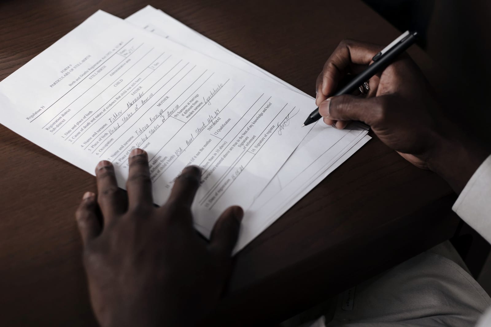 A hand signing a form